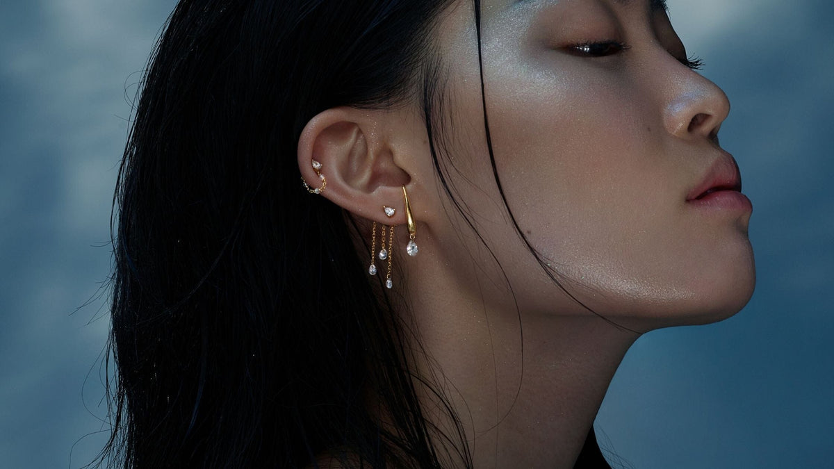 une femme de profil porte des bijoux en forme de goutte d'eau