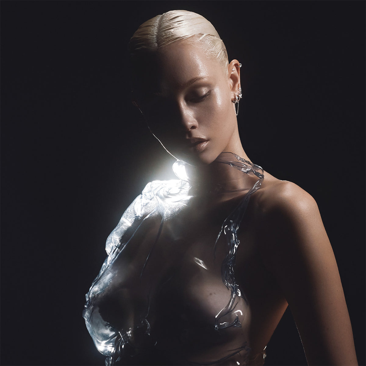 Profil de femme avec piercing d'oreille en titane, éclairage dramatique et vêtement transparent sculptural