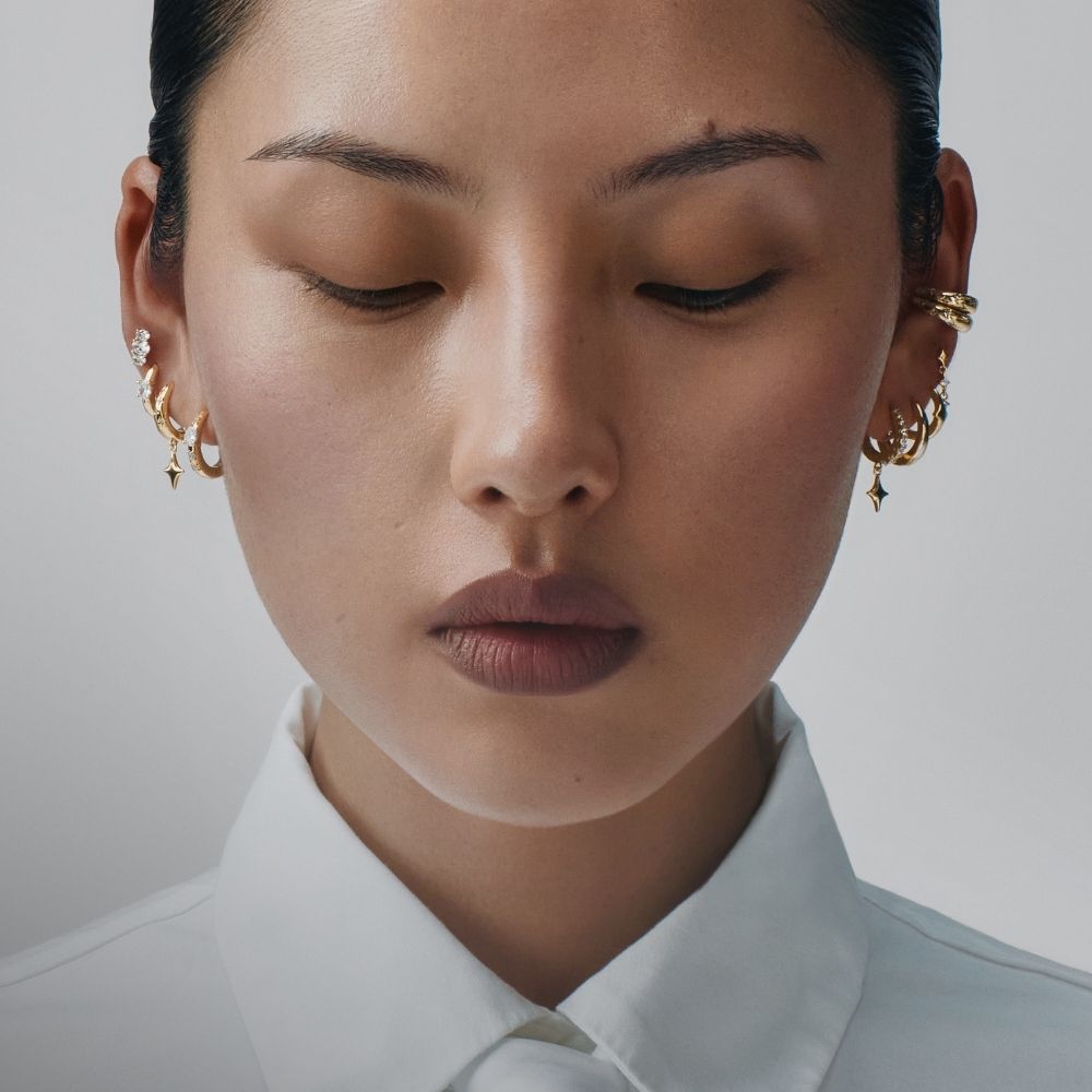 Visage de femme aux yeux fermés, bijoux d'oreille dorés ornés d'étoiles, collection Eternal