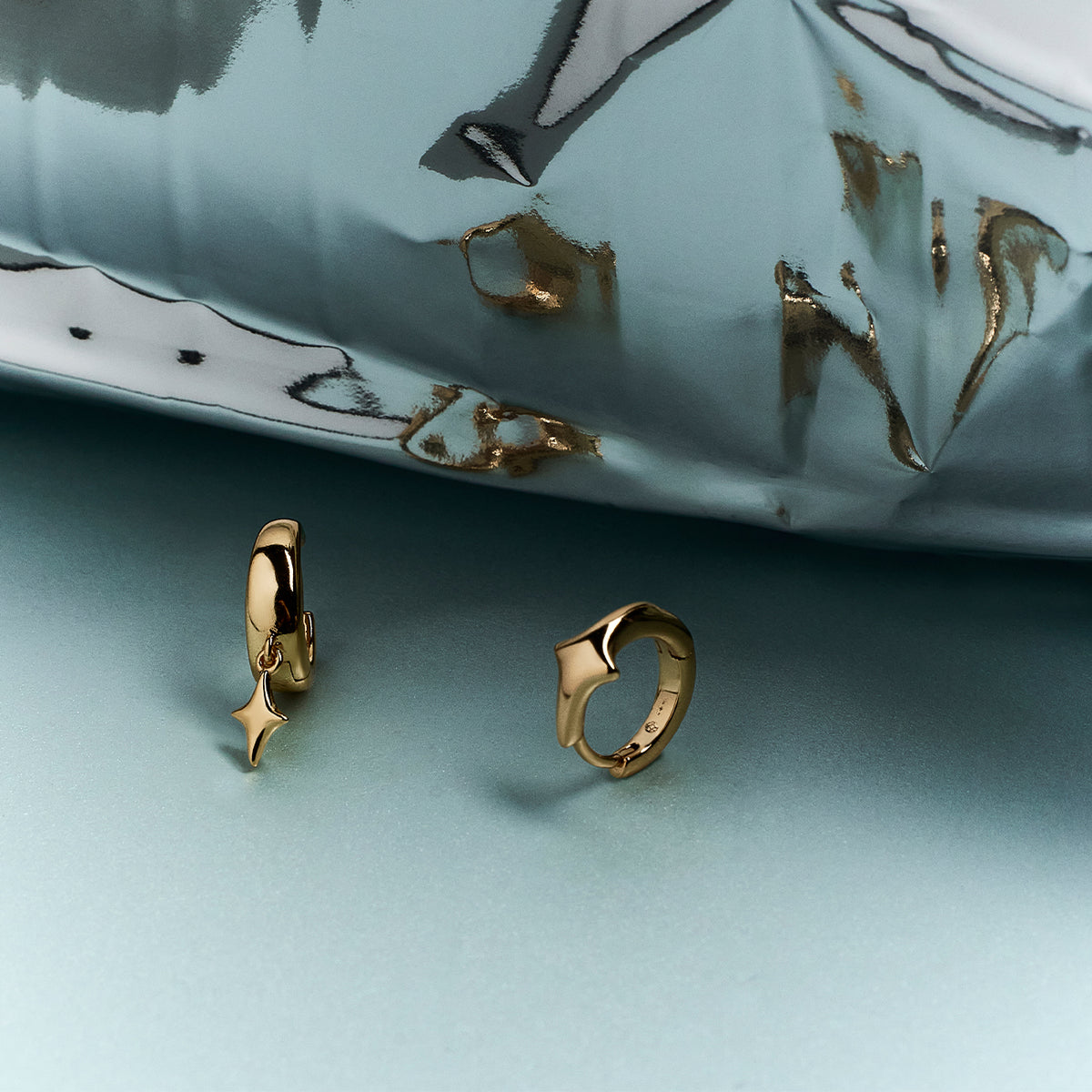 Gros plan sur deux bijoux dorés, un anneau à breloque étoile et un anneau ajustable en forme de cœur