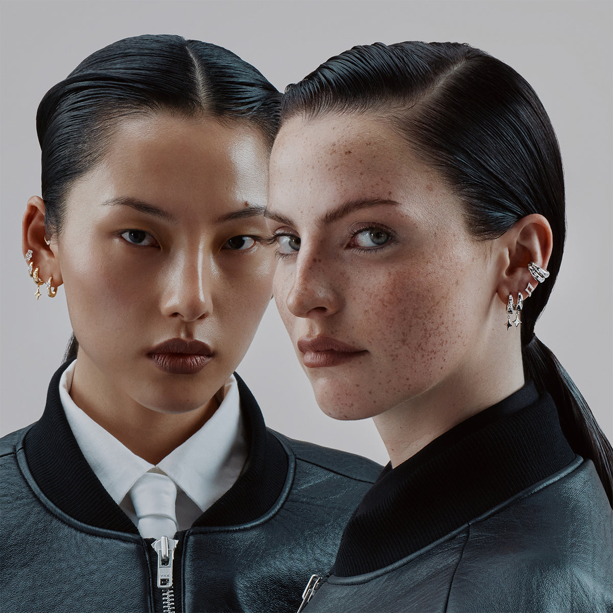Deux femmes portant plusieurs piercings et boucles d'oreilles dorées, vestes de cuir noir, gros plan visage