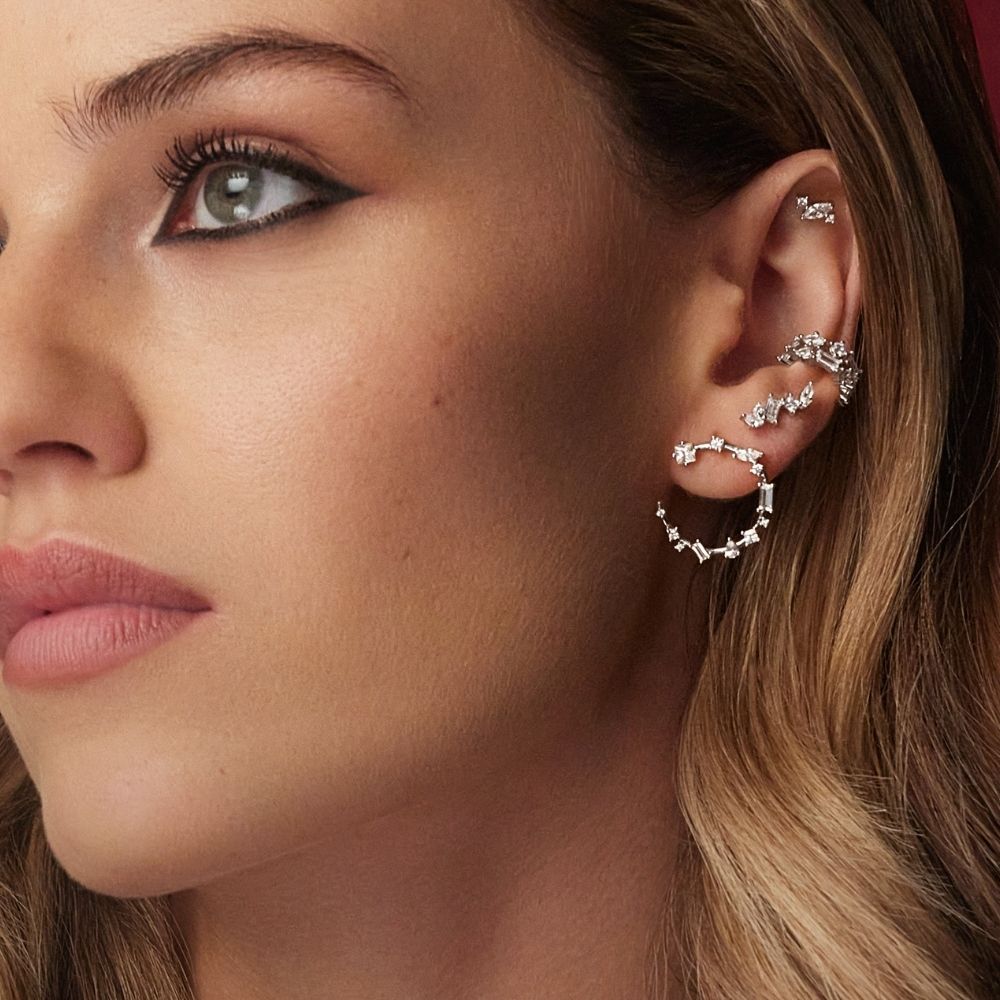 Gros plan sur une oreille multi-piercée avec créoles et boucles dorées, collection Casino