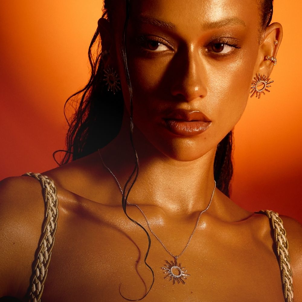 Femme portant un collier et des boucles d'oreilles en forme de soleil, collection Mon Soleil